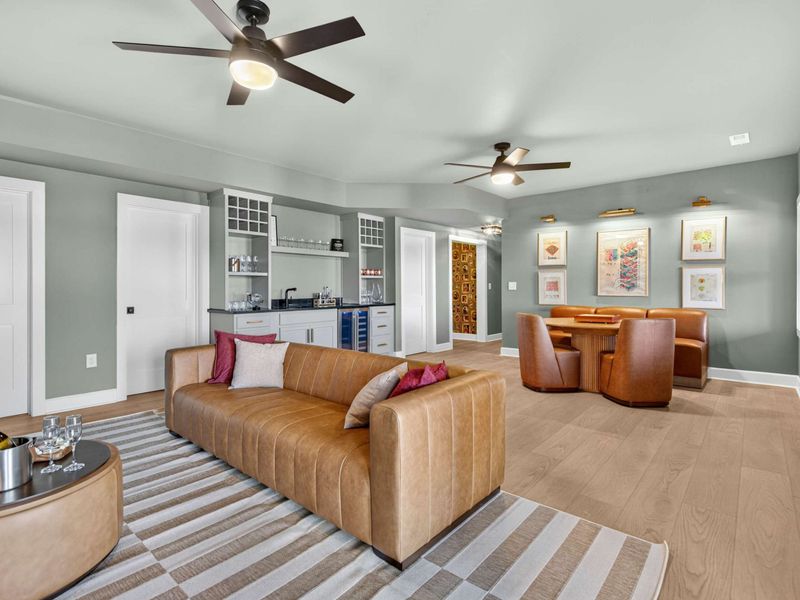 Lower Living Room - The full lower level with leather sofa, game nook, wet bar, and gallery wall under sage green walls.