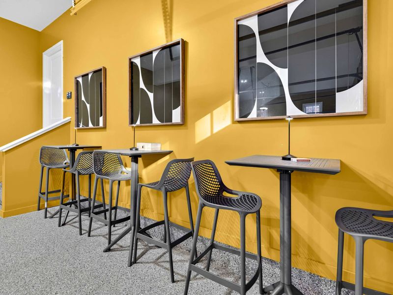 Spectator Seating - High-top tables and stools along the yellow wall, perfect for watching the games or taking a break.