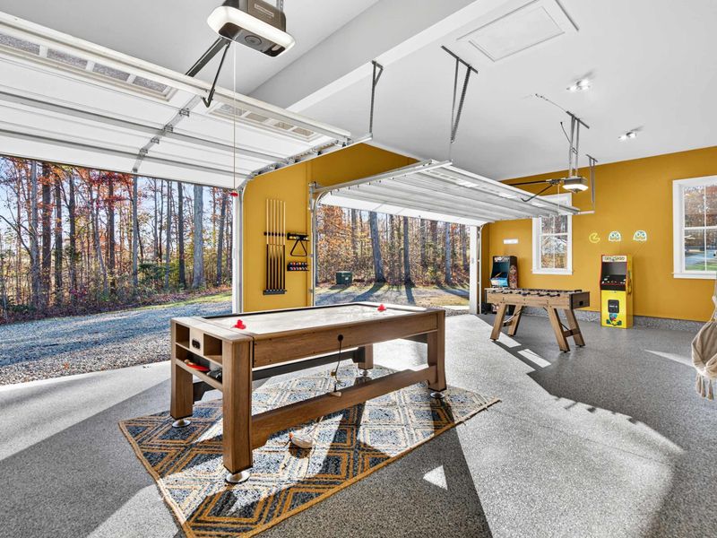 Game Room Entrance - The garage game room with air hockey, pool cue rack, and the driveway just outside the open doors.