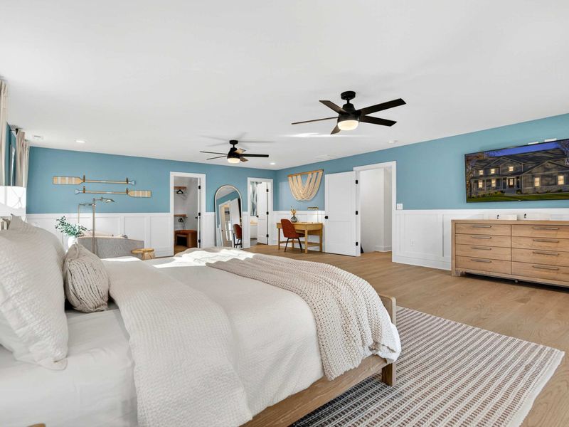 Primary Suite from the Bed - Looking toward the TV, dresser, walk-in closet archway, and ensuite bath from the king bed.