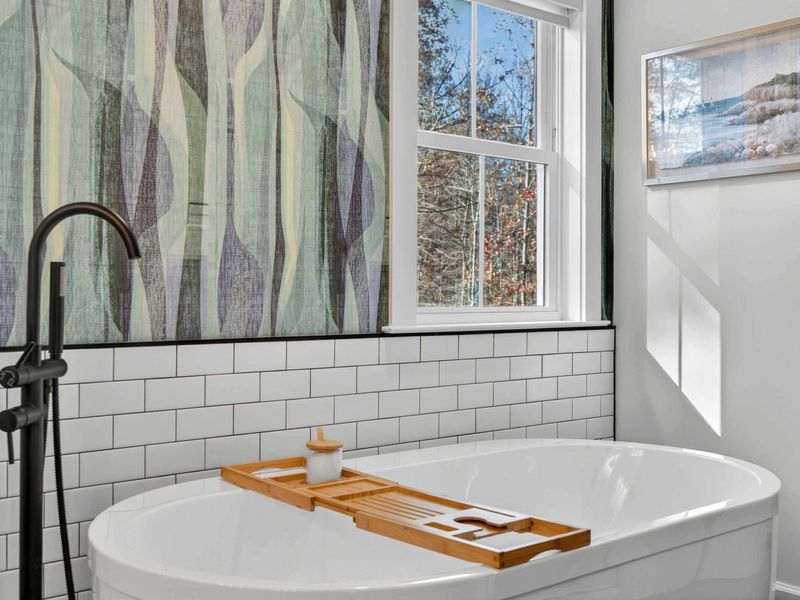Tub Detail - The soaking tub close up, with the bamboo caddy, black floor-mount faucet, and tree views through the window.