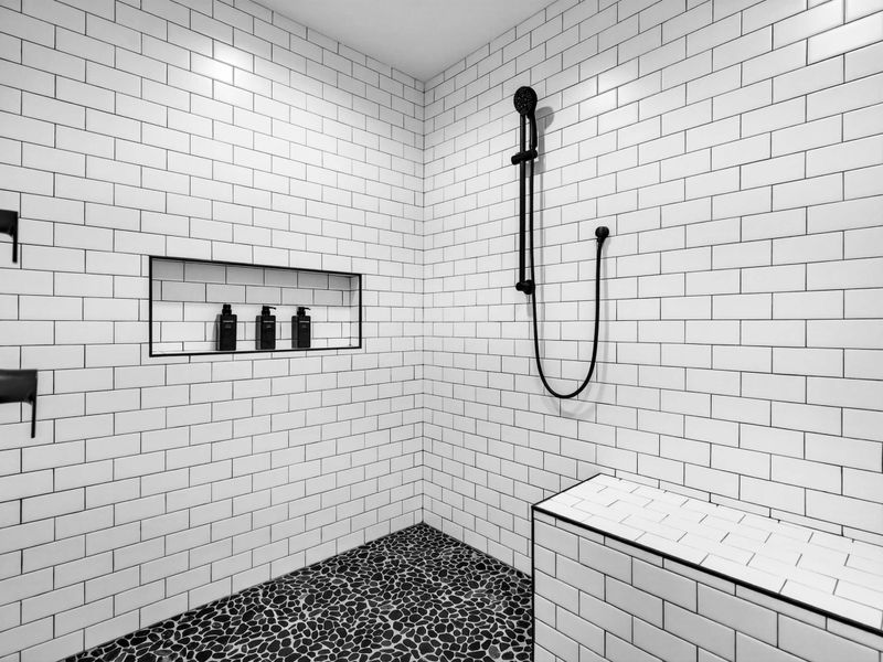 Primary Shower Detail - White subway tile, a built-in niche with toiletries, a bench, and a handheld shower inside the walk-in.