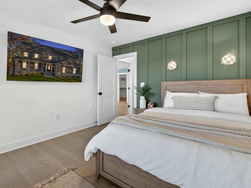 Lower Level Bedroom - A queen bed against a sage green board-and-batten accent wall, with nautical sconces and a wall-mounted TV.