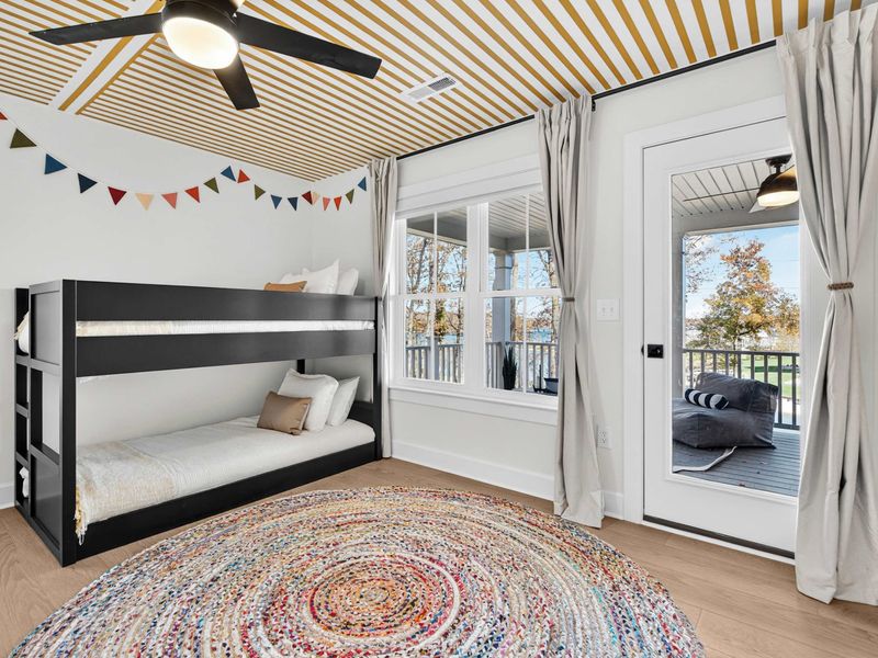 Bunk Room - A cheerful room with two bunk beds (one black, one white), striped ceiling, colorful bunting, and a braided rug.