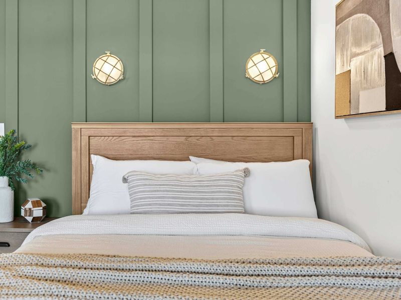 Bedroom Detail - The sage green accent wall, brass cage sconces, and layered bedding up close.