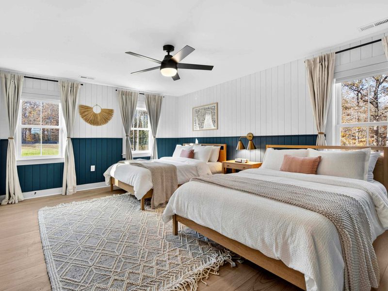Double Queen Bedroom - Two queen beds with navy and white shiplap, a woven fan accent, and windows on three sides for natural light.