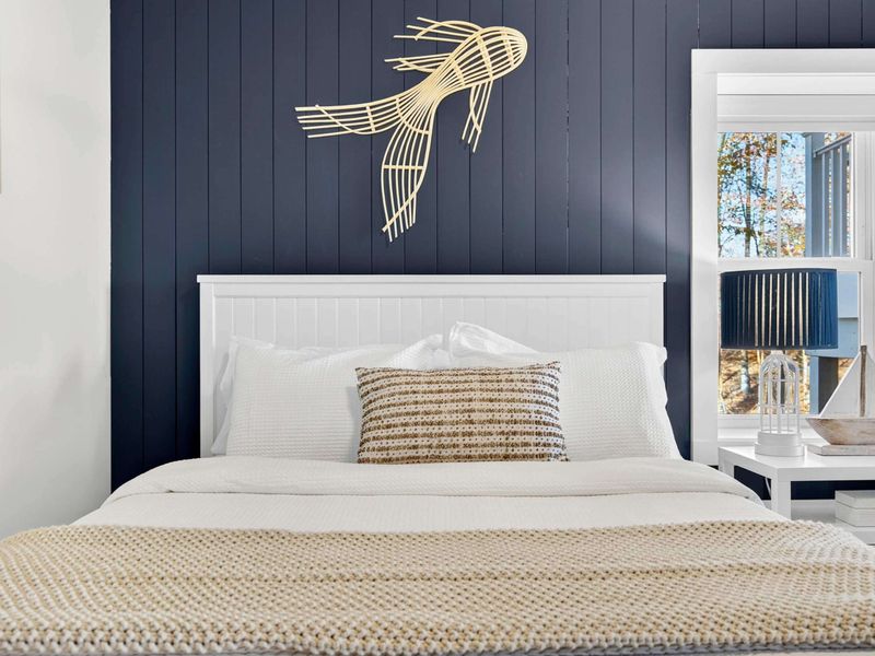 Queen Bedroom - A navy accent wall and gold wire bird art give this bedroom its own personality and a cozy feel.