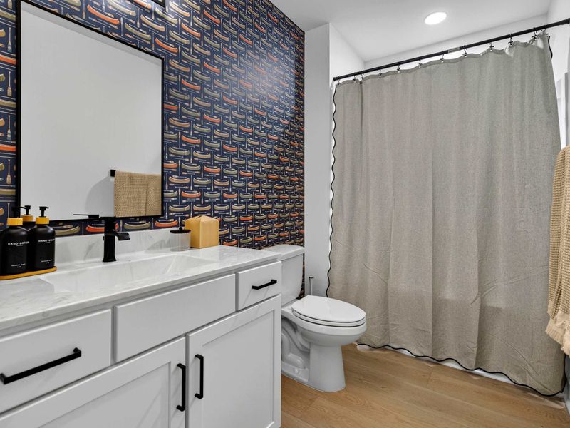 Lower Bath - Canoe-print wallpaper, a white vanity with marble top, and a curtained tub bring lake-house charm to this full bath.
