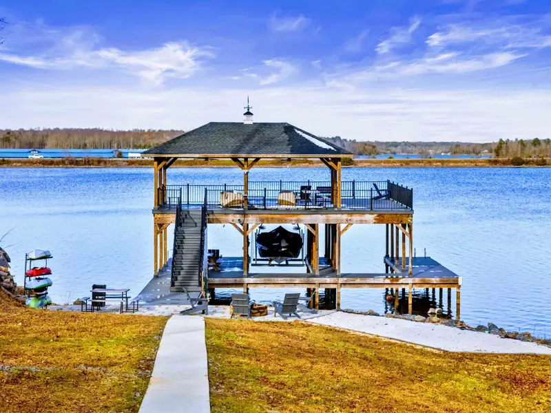 Lakefront Patio - The covered ground-level patio offers hot tub access, seating, and sweeping lake views through the trees.