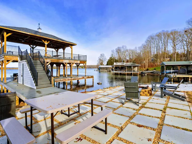 Covered Patio - The hot tub sits under cover with lake views, while outdoor seating and a gas grill round out the space.