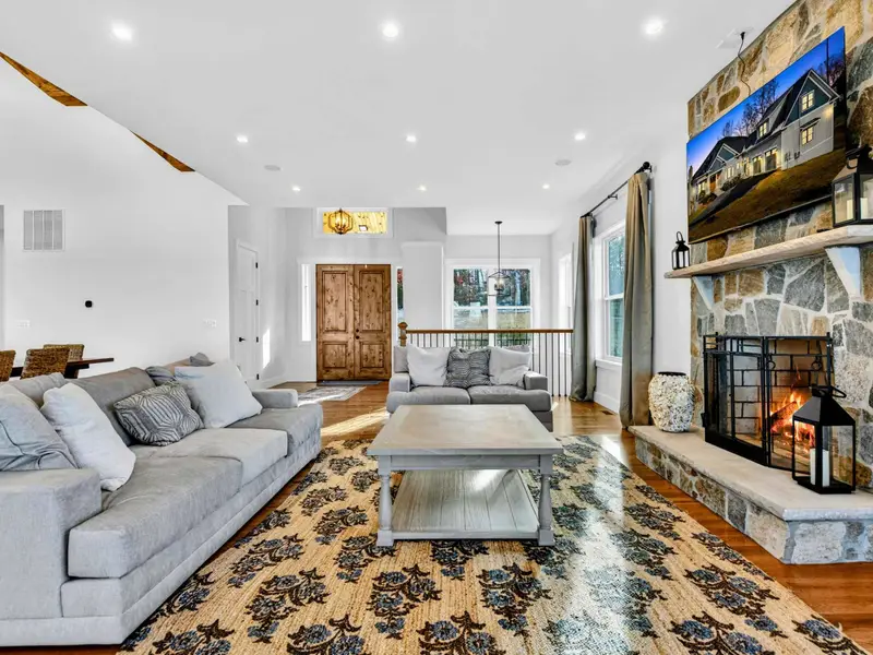 Lower Level Entry - The staircase descends to the lower-level living area, where a stone fireplace and oversized sectional await.