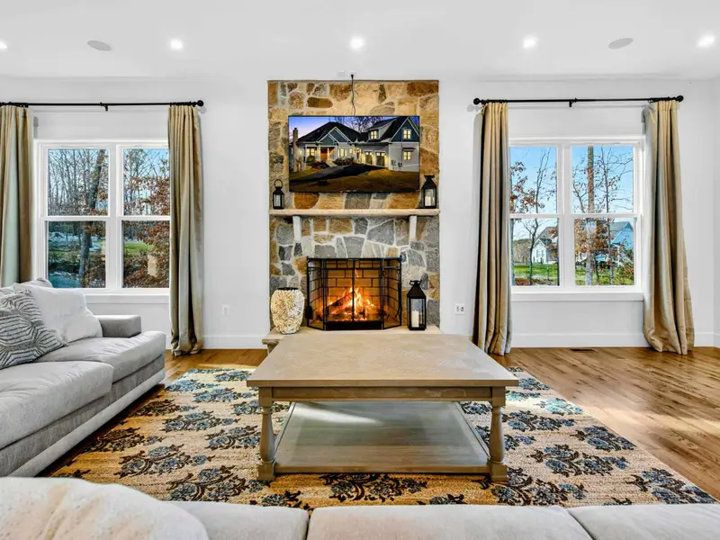 Lower Living Room - The deep sectional faces a large TV and stone fireplace, with the second kitchen visible beyond.