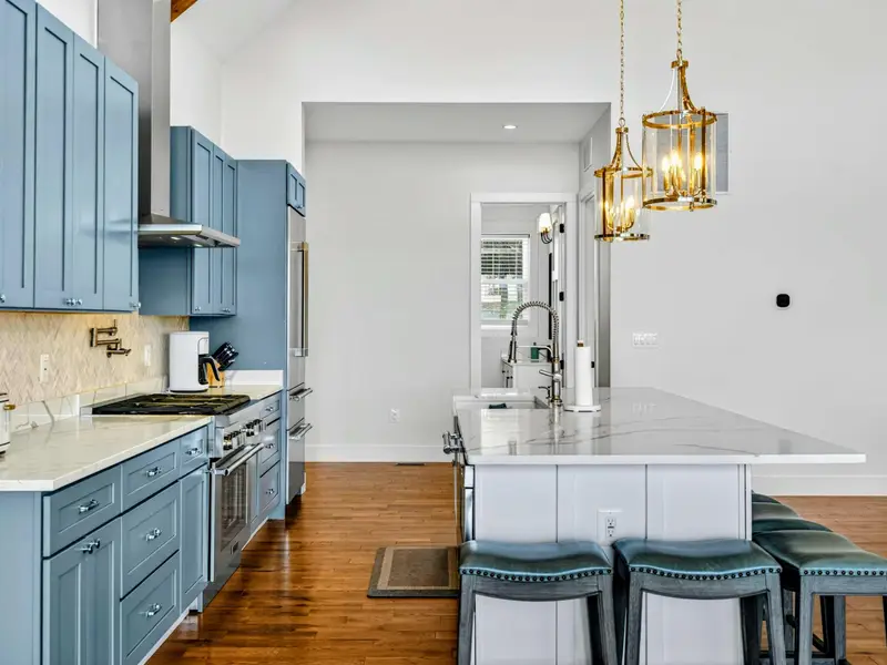 Lower Kitchen Range - Professional-style range, open wood shelves, and lake views through the windows beyond the island.