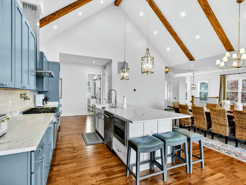 Lower Level Open Plan - The kitchen island, living area, and stone fireplace flow together, with lake views through the windows and patio access.
