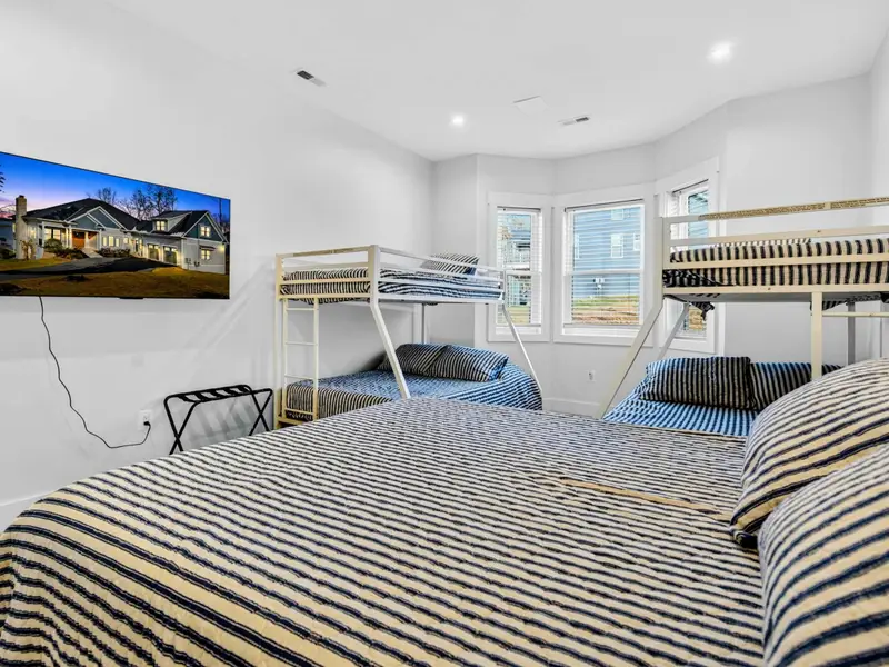 Bunk Room - From the queen bed side, a wall-mounted TV and coordinated navy striped bedding tie the room together.