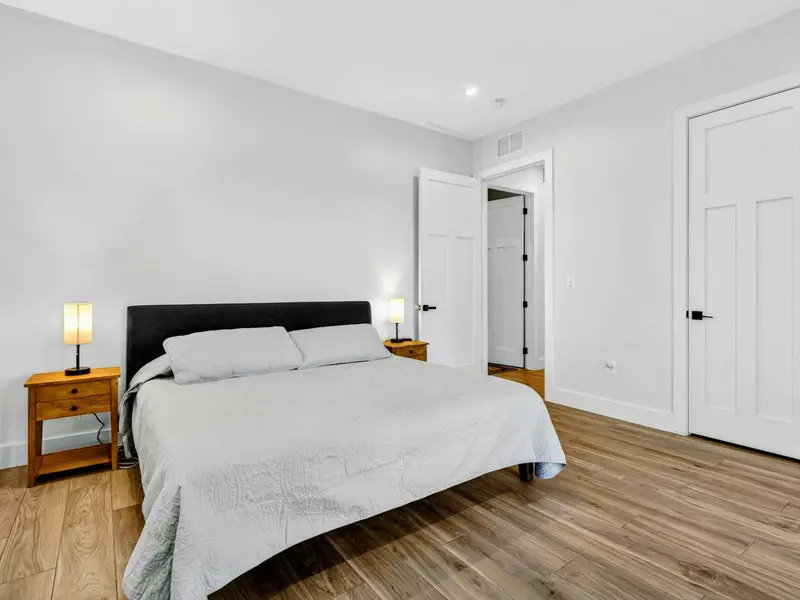 Lower King Bedroom - A dark upholstered headboard, wood nightstands, and a doorway to the ensuite bathroom.
