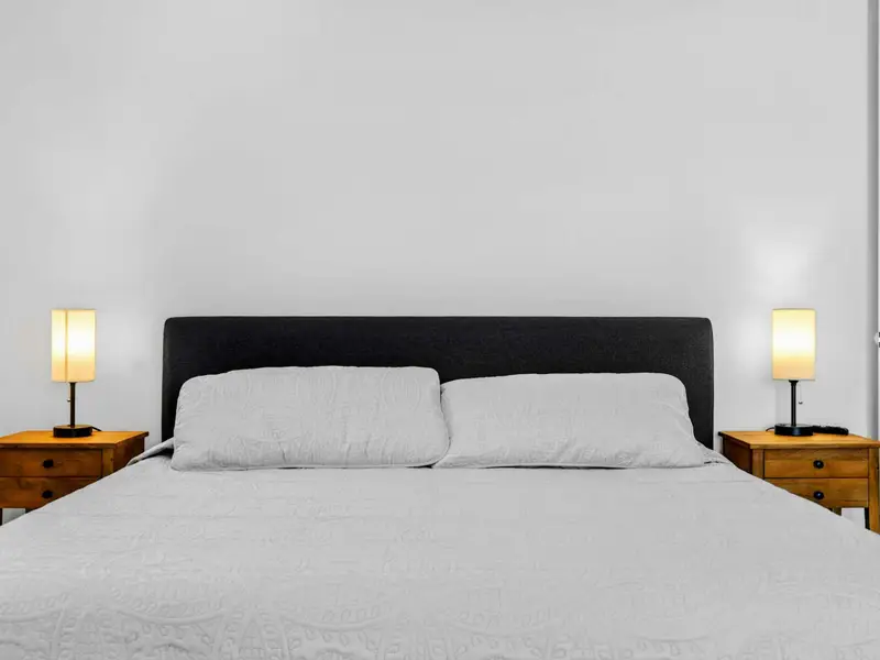 Bedding Detail - A dark upholstered headboard and matching wood nightstands bring a modern, restful feel to this bedroom.