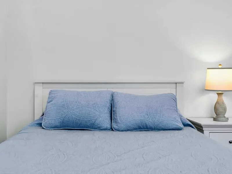 Bedding Detail - Soft quilted bedding and matching pillows in calming blue tones set a restful scene.