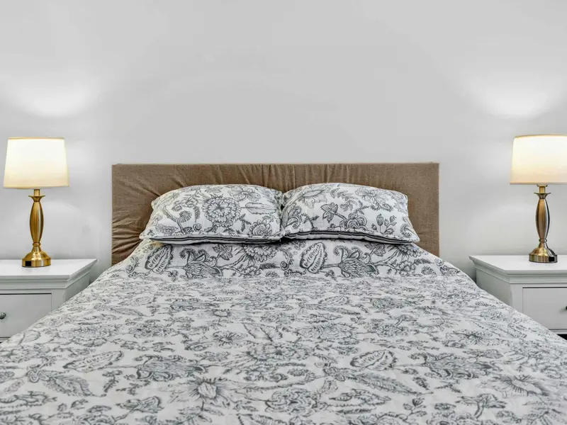 Bedding Detail - Matching lamps and an upholstered headboard frame the queen bed in the lower-level guest room.