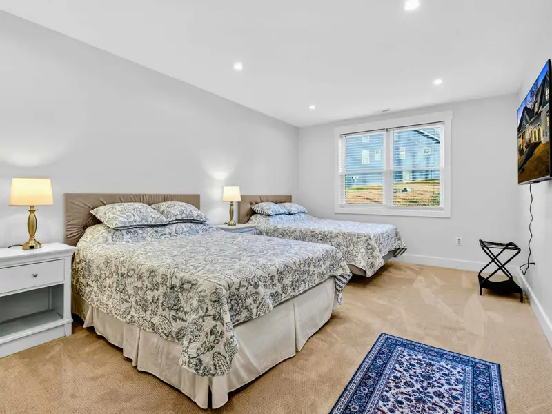 Lower Bedroom 6 - Two queen beds with coordinated floral bedding, a wall-mounted TV, and a small accent rug.
