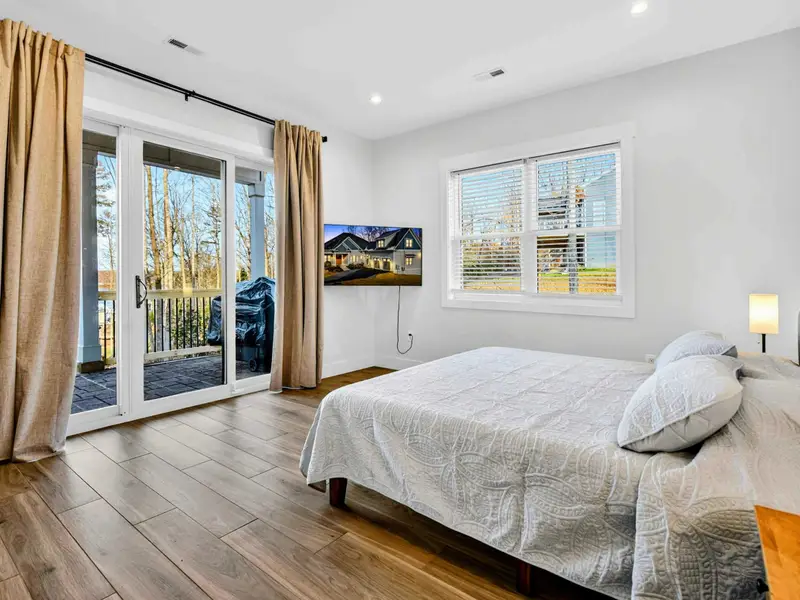 Lower King Bedroom - Sliding glass doors open to the covered patio, with a mounted TV and gold drapes framing the view.