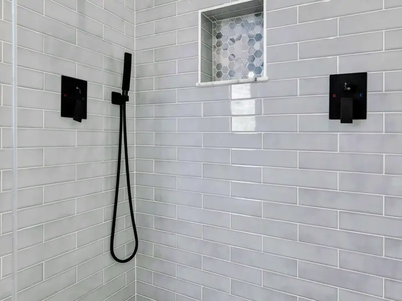 Lower Bath 2 - A double vanity with patterned floor tile, black fixtures, and access to the tub-shower room.