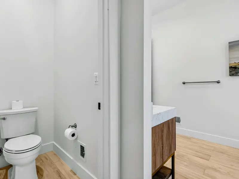 Lower Bath 2 Tub - Dark subway tile surrounds the tub-shower, with a rain shower head and clean white fixtures.