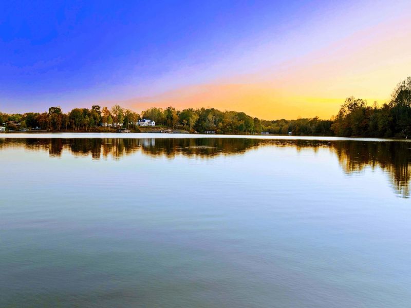 Lake View - Panoramic sunset reflecting off the calm water with tree-lined shores glowing in warm color.