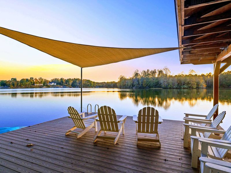 Dock - Golden hour settles over the lake as Adirondack chairs and the covered boathouse catch the last light of the day.