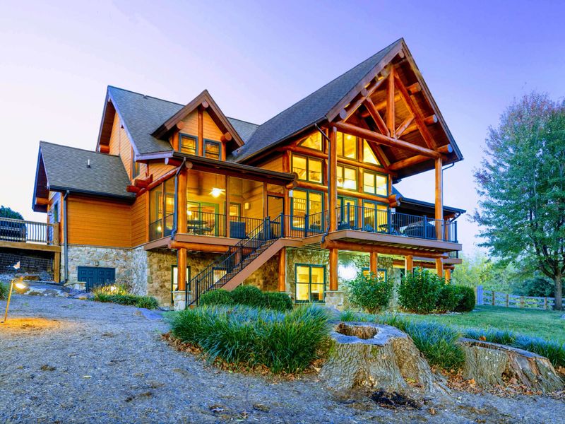 Exterior - Dramatic timber A-frame peaks and warm light from floor-to-ceiling windows welcome you at dusk.