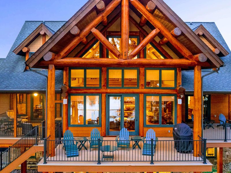 Exterior - Teal Adirondack chairs line the rear deck beneath the massive timber A-frame entry with floor-to-ceiling windows.