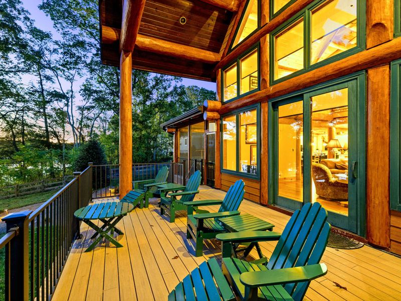 Deck - Blue Adirondack chairs along the railing at dusk, with the warm glow from the home's windows behind.