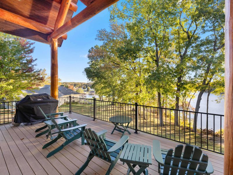 Deck - Adirondack chairs and a gas grill on the composite deck with lake views framed by timber posts.