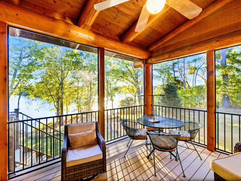 Screened Porch - Wicker seating and a bistro table under a ceiling fan, all wrapped in timber beams with lake views through the screens.