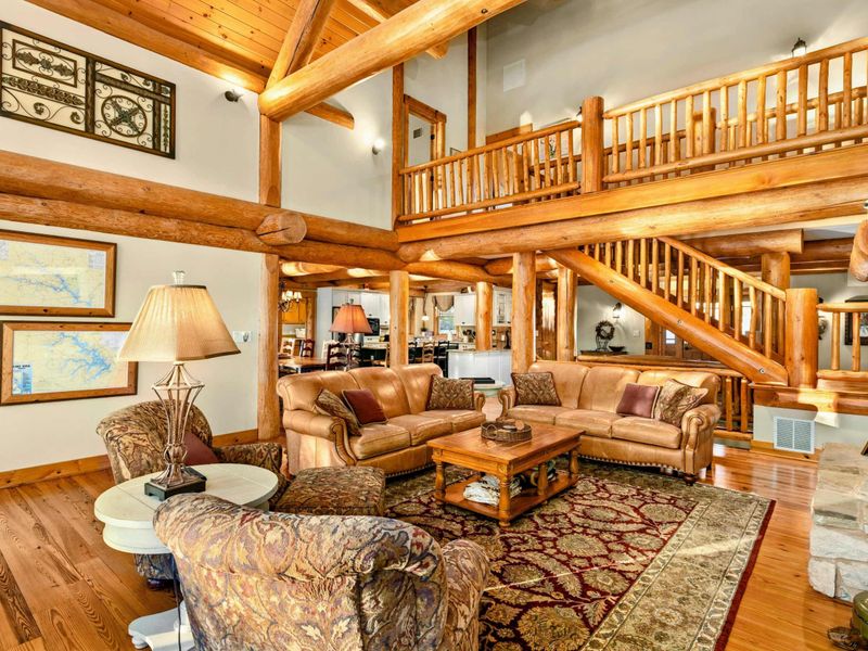 Great Room - Leather sofas and accent chairs gather beneath the log beam ceiling and open loft with log railing.