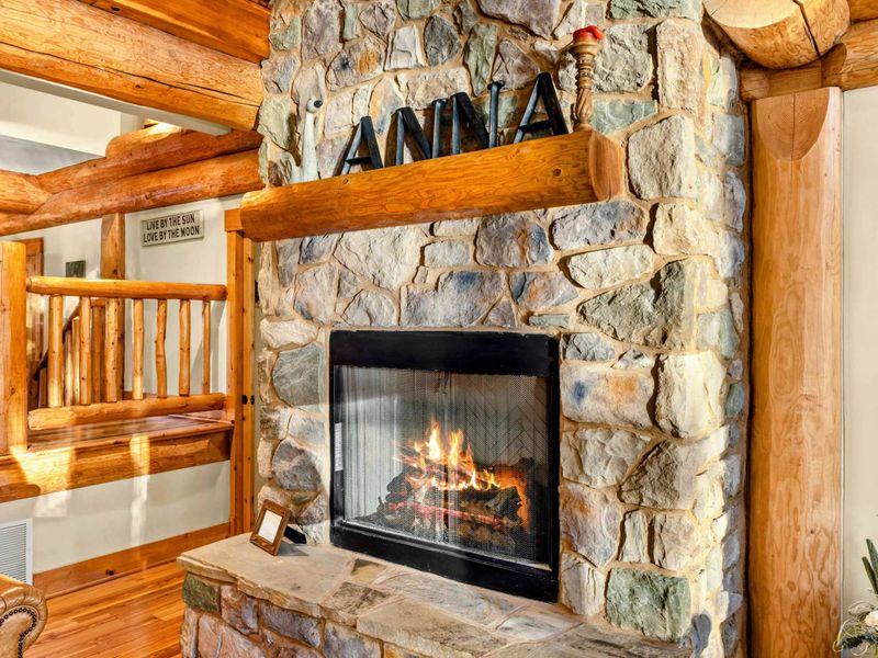 Fireplace - Fieldstone fireplace with a crackling fire, log beam mantel, and decorative lettering adds warmth to the great room.
