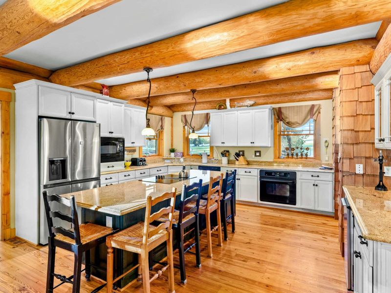 Kitchen - Full view of the well-equipped kitchen with island seating, log beam ceiling, and stainless appliances.