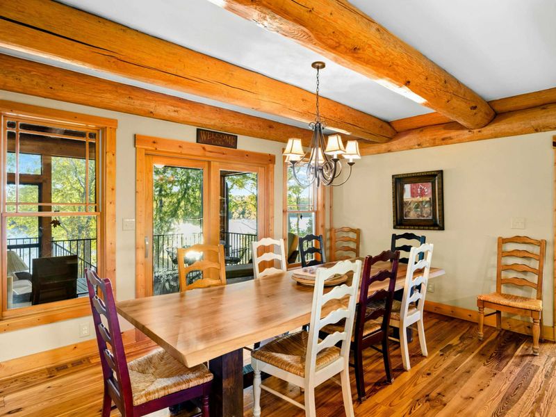 Dining Room - Ladder-back chairs surround the farmhouse table with a chandelier overhead and windows looking out to the deck.
