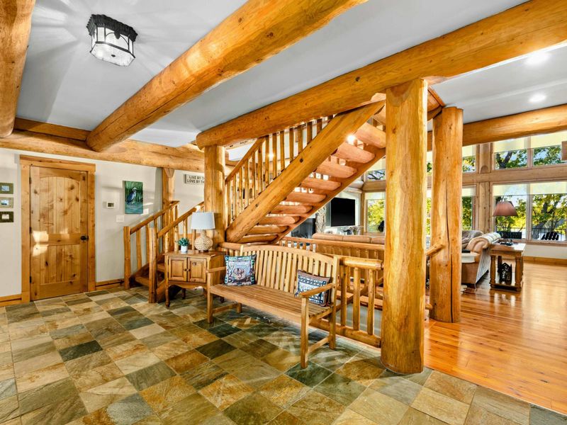 Foyer - Slate tile entry with a log staircase, wooden bench, and log beam accents welcoming you into the home.