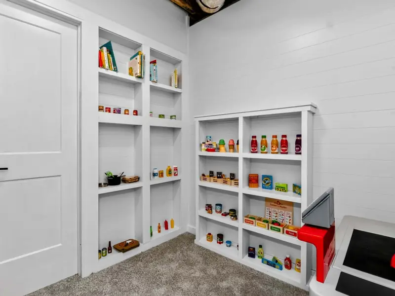 Market Interior - Inside the playhouse, built-in shelves hold play groceries, a toy cash register, and books, creating a fully imagined world for kids.