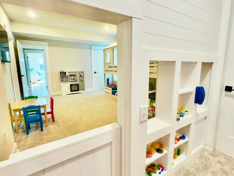 Playhouse Entry - Looking through the half-door into the bunk room, with the kids' table, bunk beds, and built-in display shelves all visible. We have a closet full of kids toys, books, puzzles, tiles! We've thought of everything!