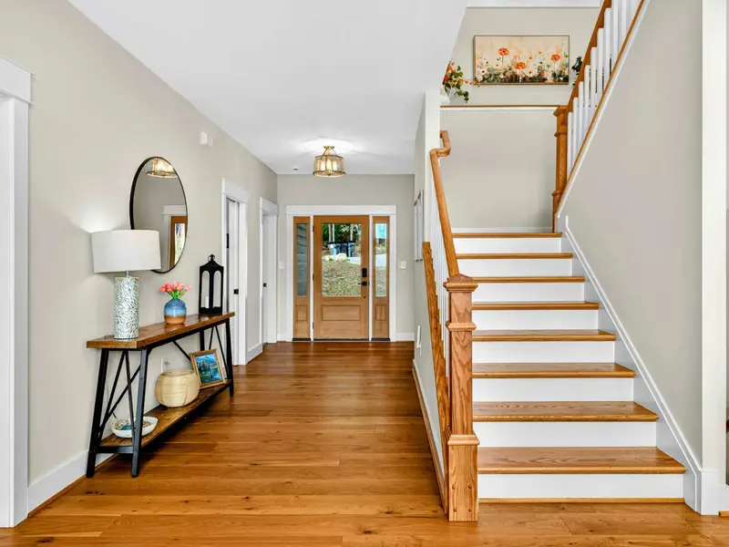 Front Entry - A welcoming foyer with hardwood floors, a console table, and the staircase to the upper level loft and bedrooms.