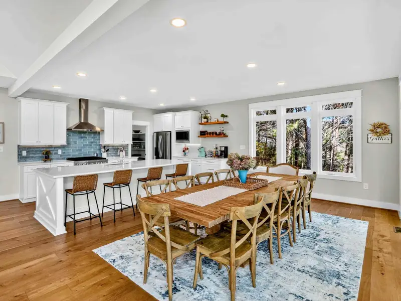 Dining and Kitchen - The full dining and kitchen area with the farmhouse table, island barstools, and screened porch doors just to the right.