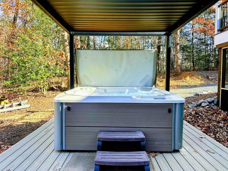 Hot Tub - Covered hot tub in the fall with stepping stones and the wooded hillside beyond.