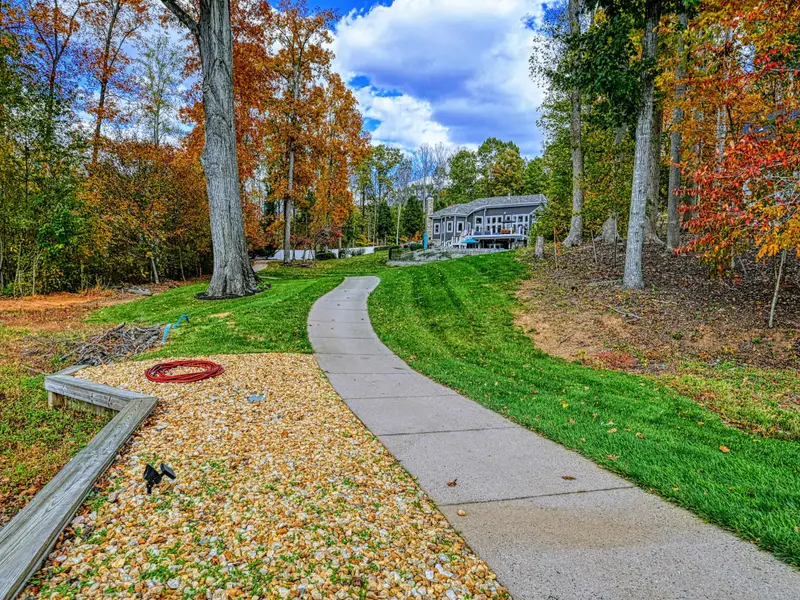 Professionally manicured lawn with dramatic stripes, sculpted gardens, and curated pathways.
