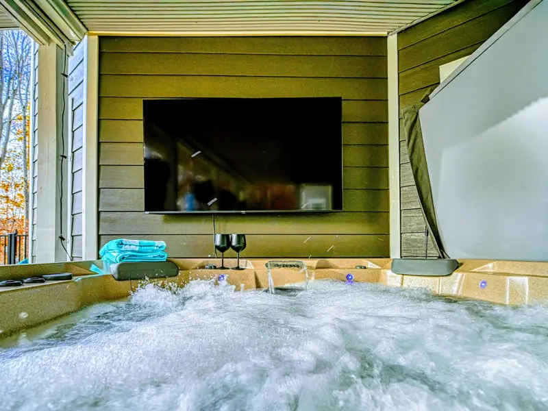 Relax and unwind in the private hot tub, where bubbling waters, a mounted TV, and peaceful outdoor surroundings create the perfect spot for year-round relaxation.