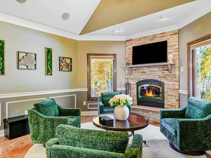 The Green Room is a cozy second living space with deep green swivel chairs, warm textures, and views of the trees—perfect for chatting with the chef, curling up by the fireplace, or lingering over games, wine, and conversation.