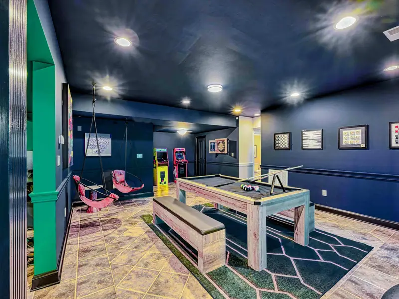 The Billiard & Games Lounge is a lower-level play hub with a convertible pool/ping-pong/dining table, darts, arcade and wall games, leather swings, and direct patio access—designed for laughter, competition, and all-ages fun.