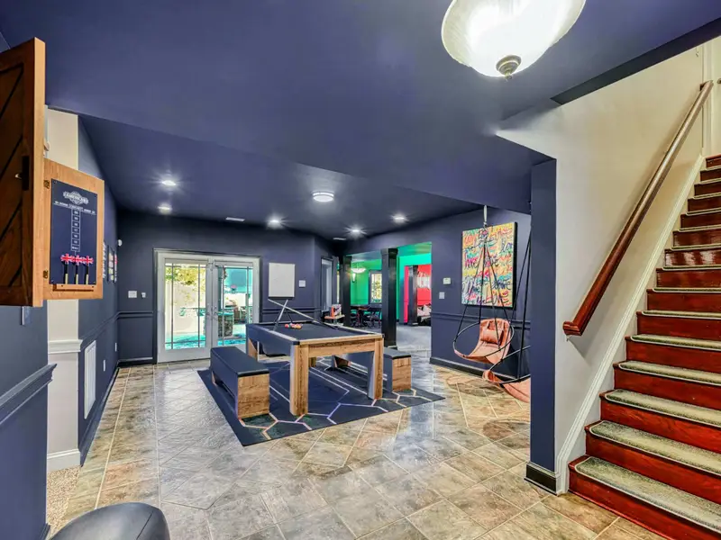 The Billiard & Games Lounge is a lower-level play hub with a convertible pool/ping-pong/dining table, darts, arcade and wall games, leather swings, and direct patio access—designed for laughter, competition, and all-ages fun.