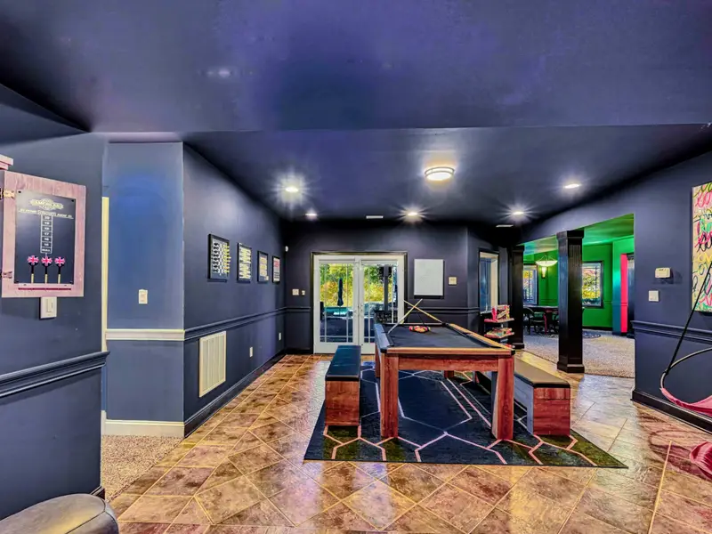 The Billiard & Games Lounge is a lower-level play hub with a convertible pool/ping-pong/dining table, darts, arcade and wall games, leather swings, and direct patio access—designed for laughter, competition, and all-ages fun.